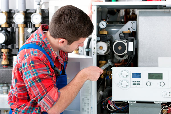 HVAC technician inspecting and repairing boiler controls in Salt Lake City