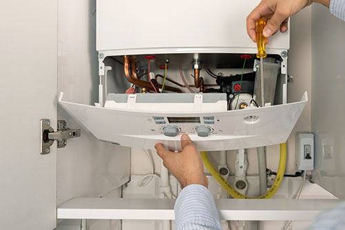 HVAC technician repairing an indoor boiler in Salt Lake City
